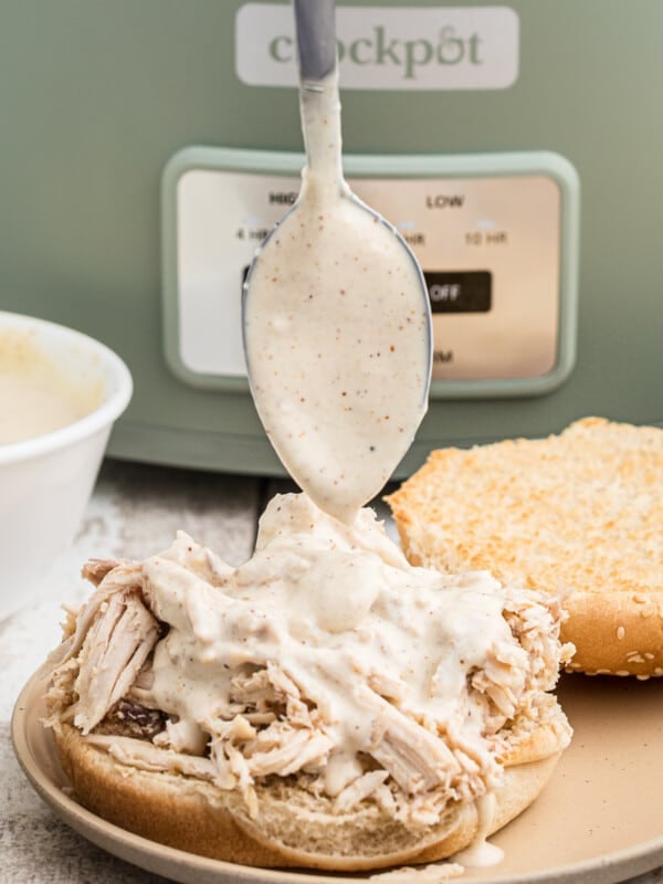 Alabama sauce being poured over a chicken sandwich.
