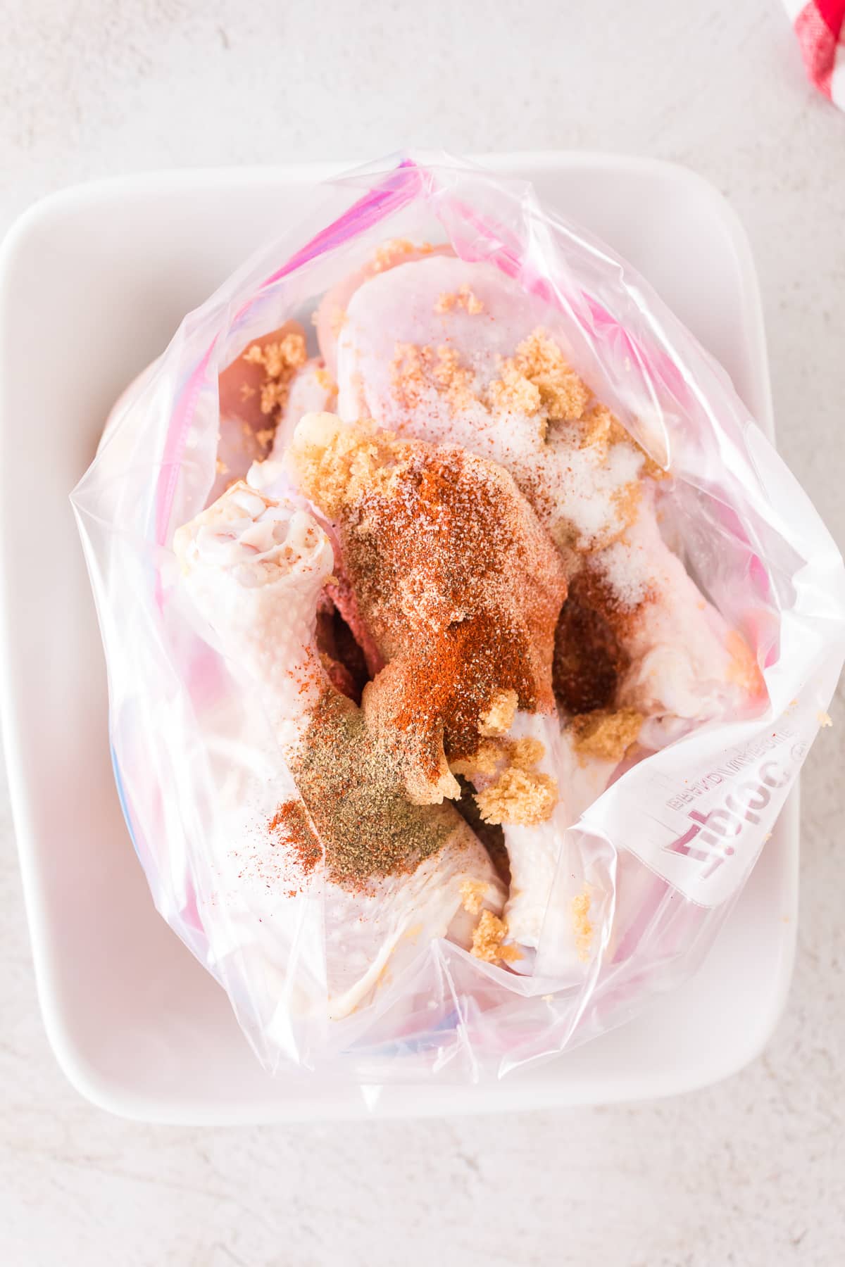 Raw drumsticks in a bag with seasonings on top.