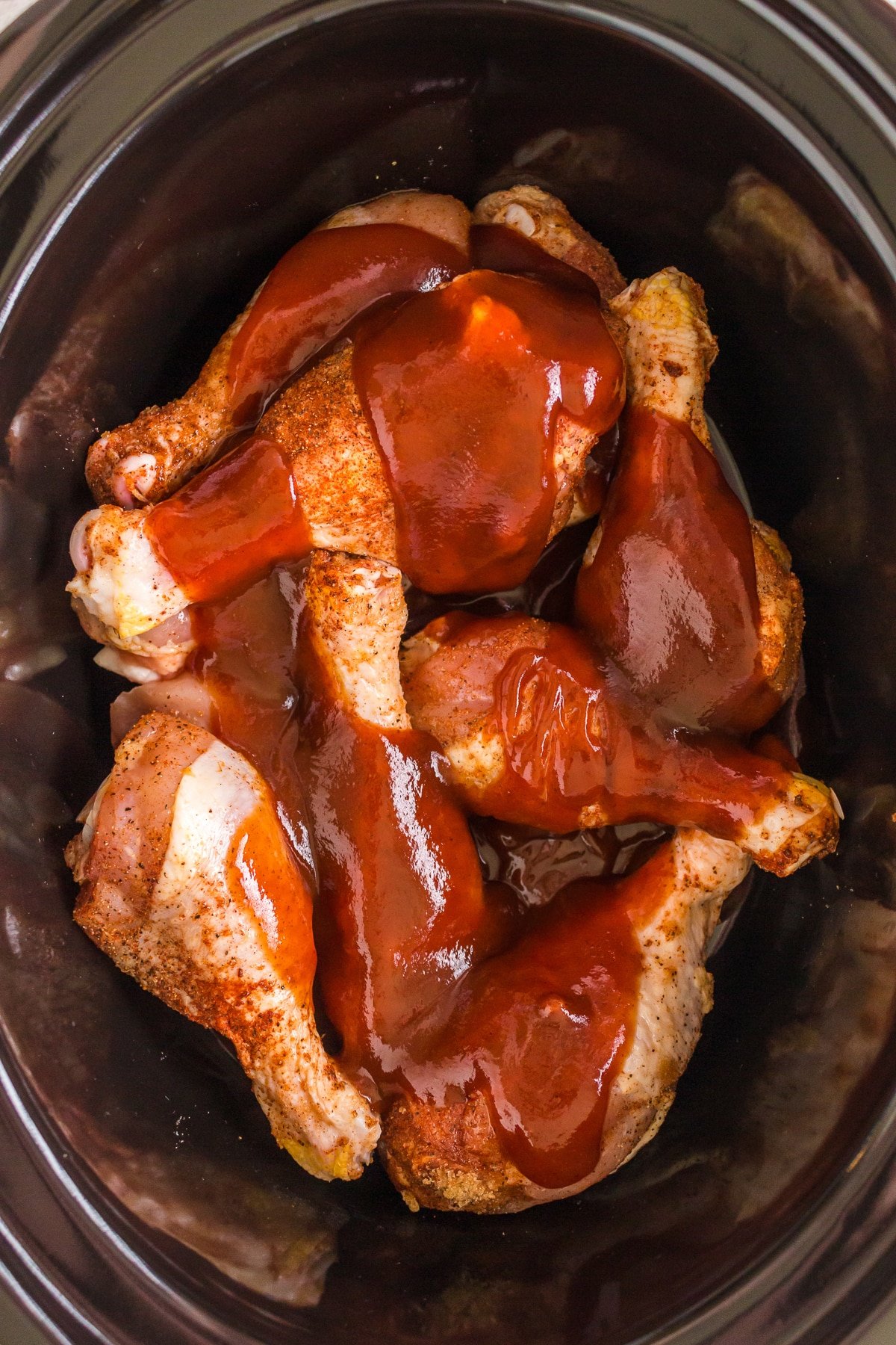 drumsticks in a slow cooker with seasonings and bbq sauce..
