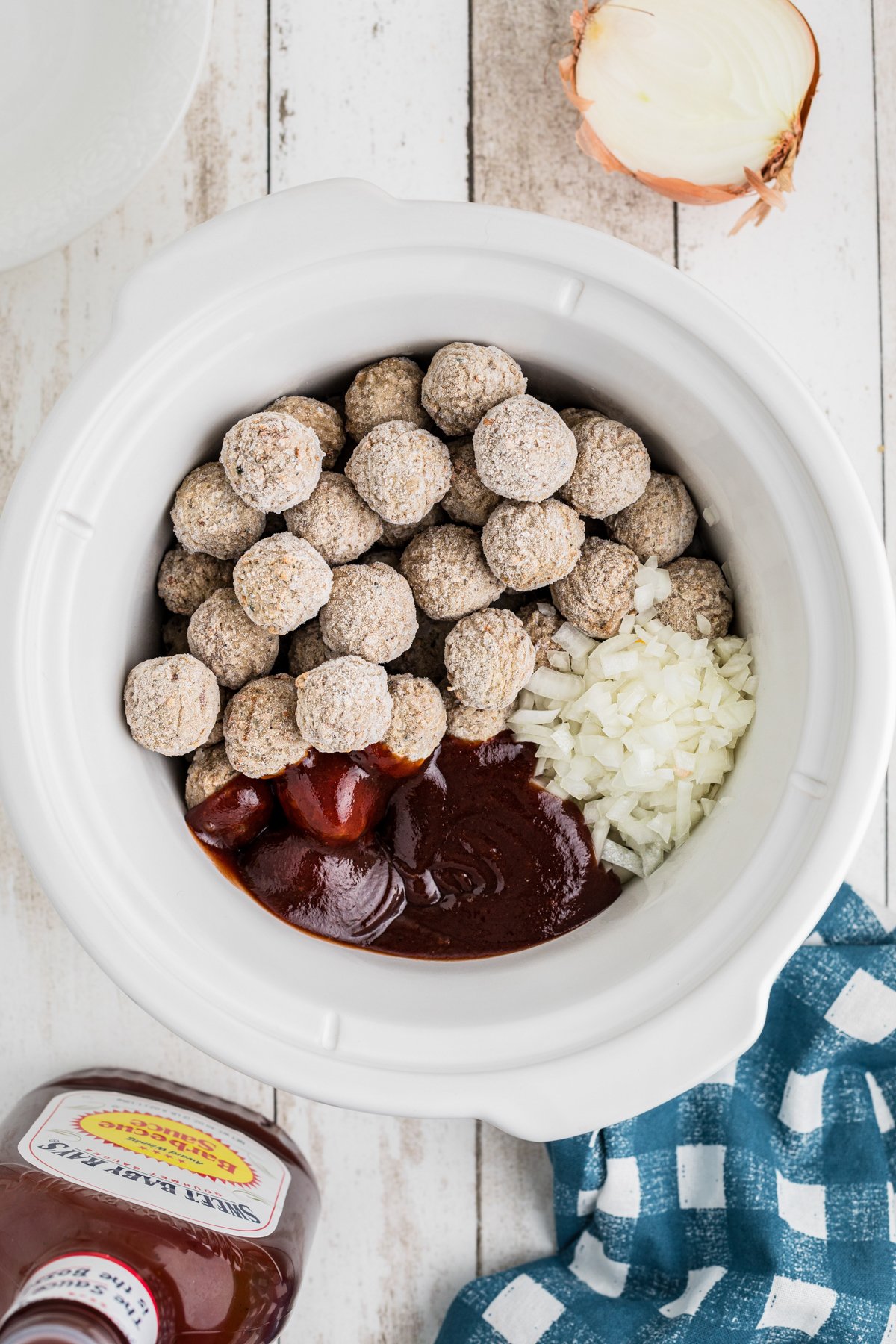 frozen meatballs in a slow cooker with bbq sauce and onion.
