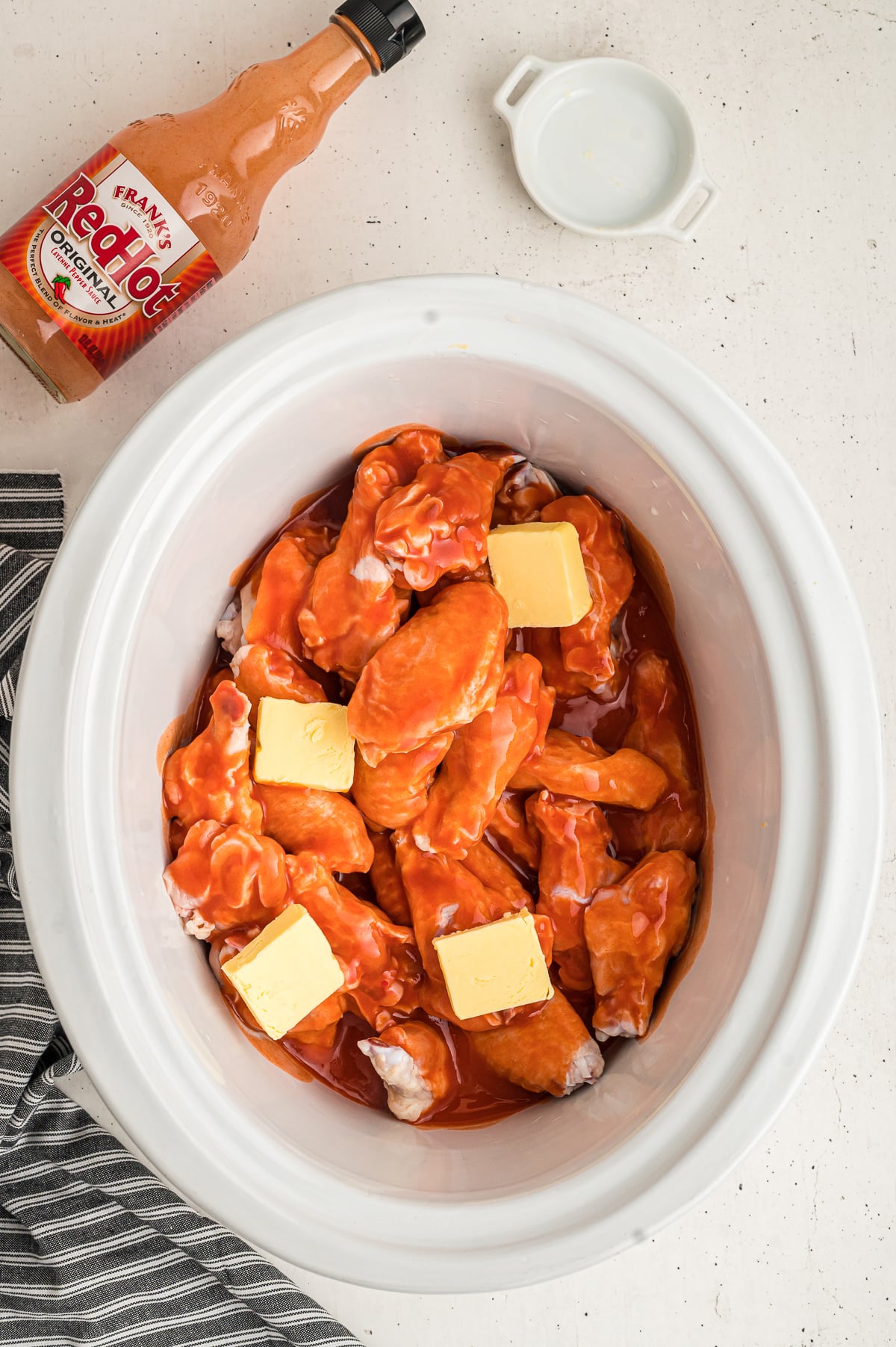 buffalo wings in crockpot with butter and buffalo sauce.