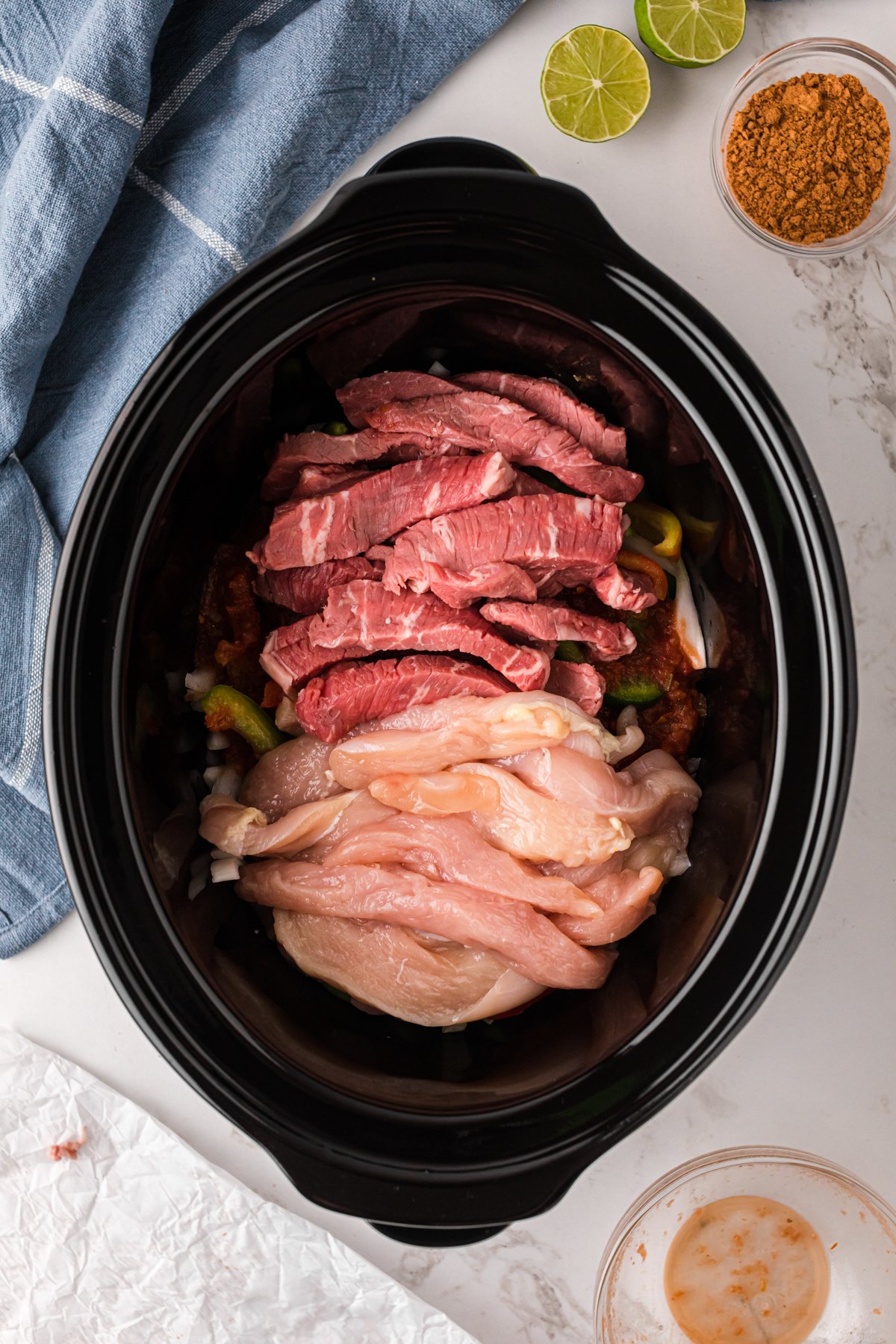 Steak and chicken added to a slow cooker.