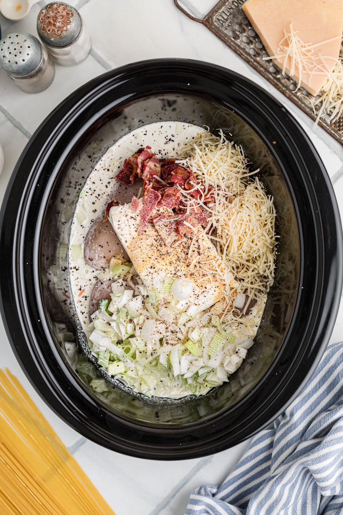 Carbonara sauce ingredients added to chicken in a slow cooker.