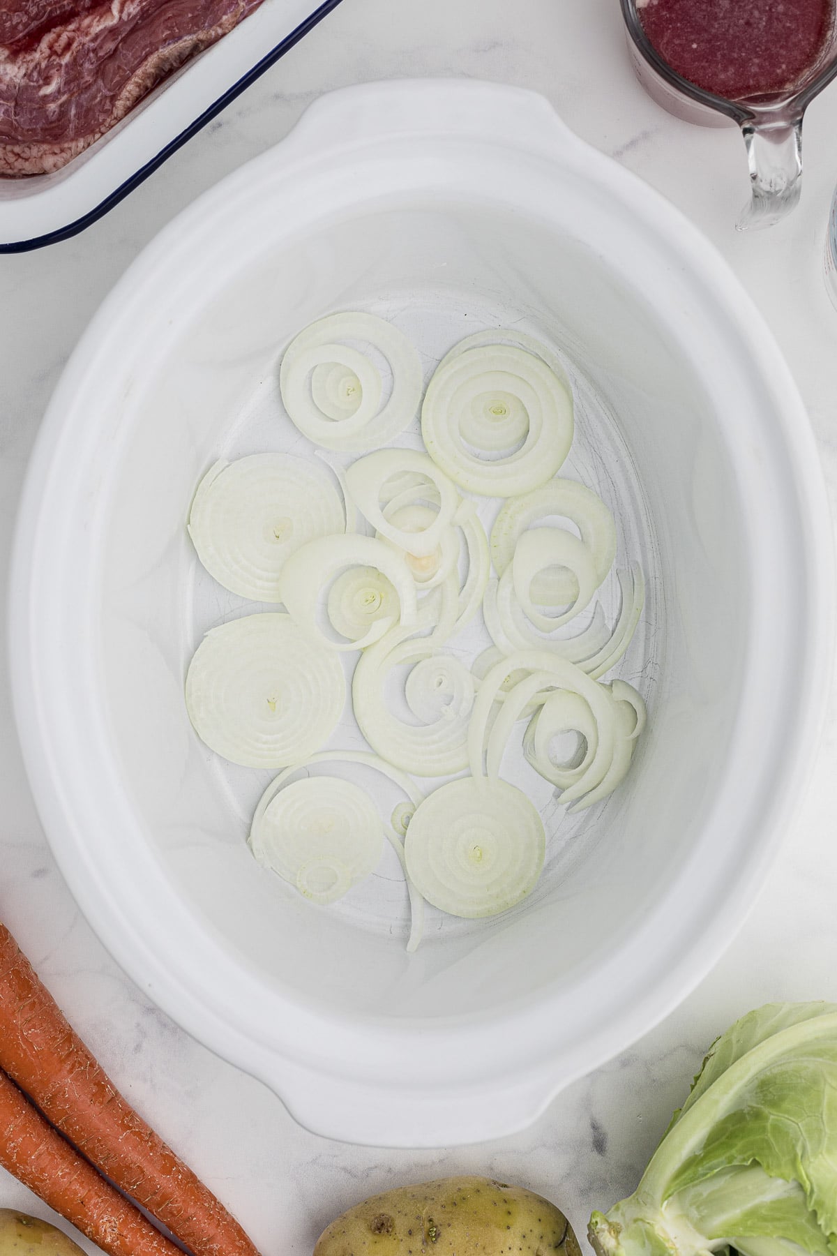 Onion in the bottom of a slow cooker.