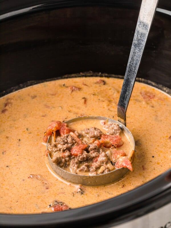 A ladleful of creamy taco soup in a crockpot.