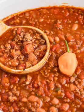 chili in as slow cooker with spoon and habanero on top.