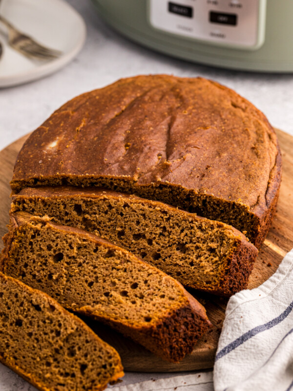 Pumpkin bread on a cutting board in front of a slow cooker.