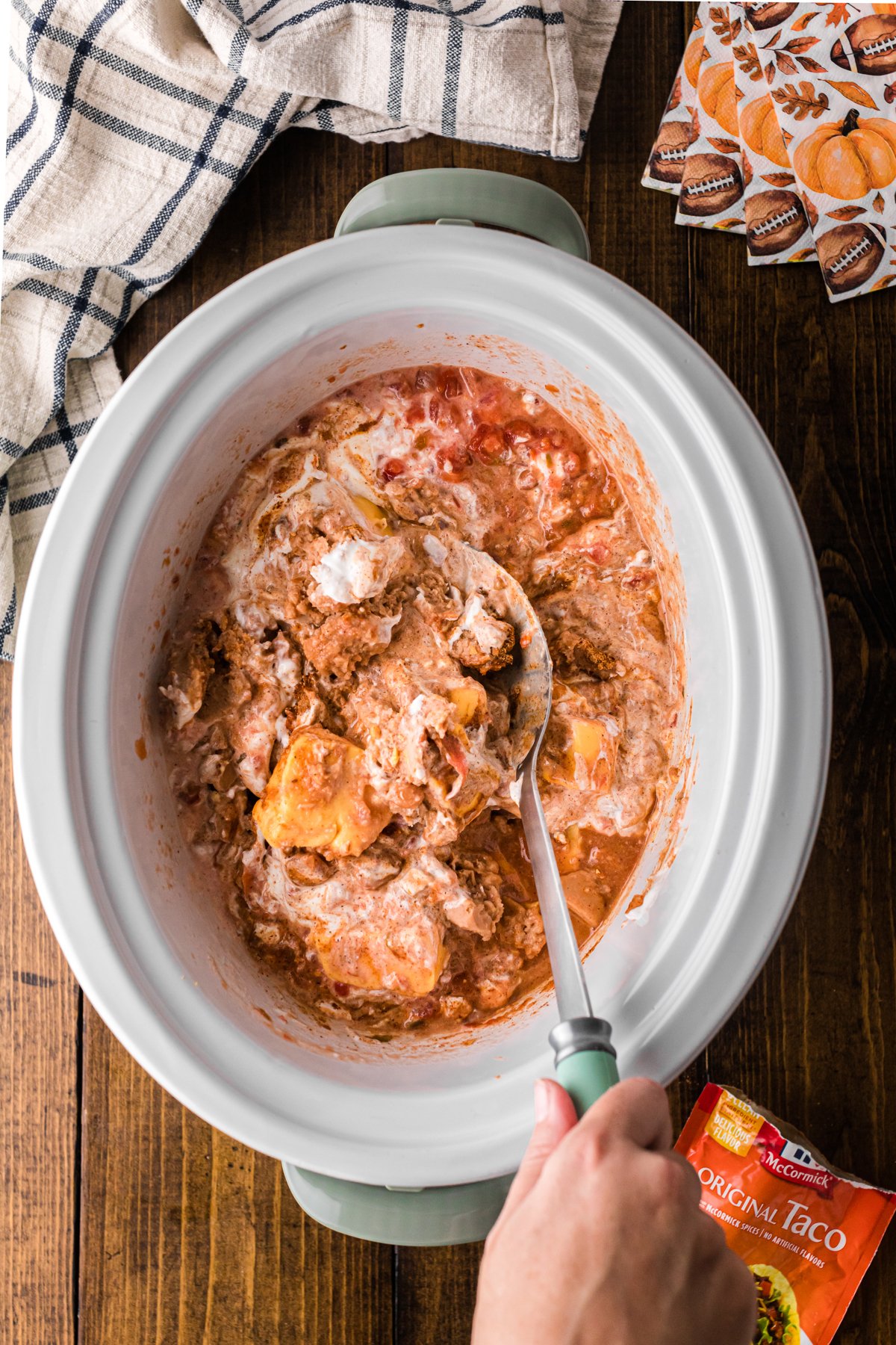 A spoon mixing the ingredients for football dip in a crockpot.
