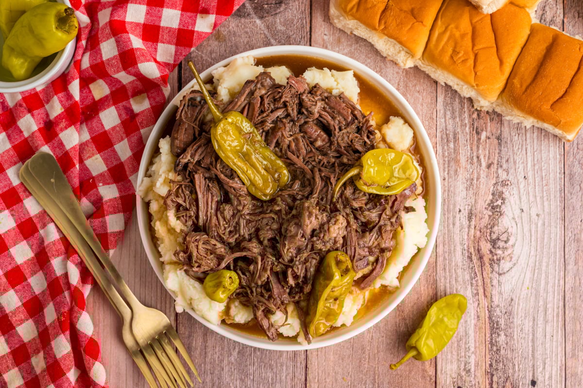 overhead shot of slow cooker Mississippi pot roast in a bowl with mashed potatoes.