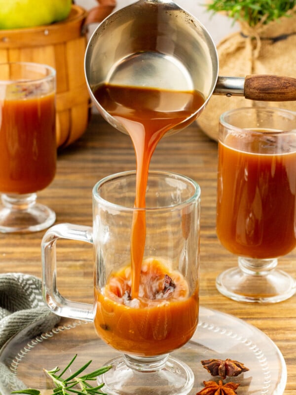 Pear cider being poured into a clear tall mug.