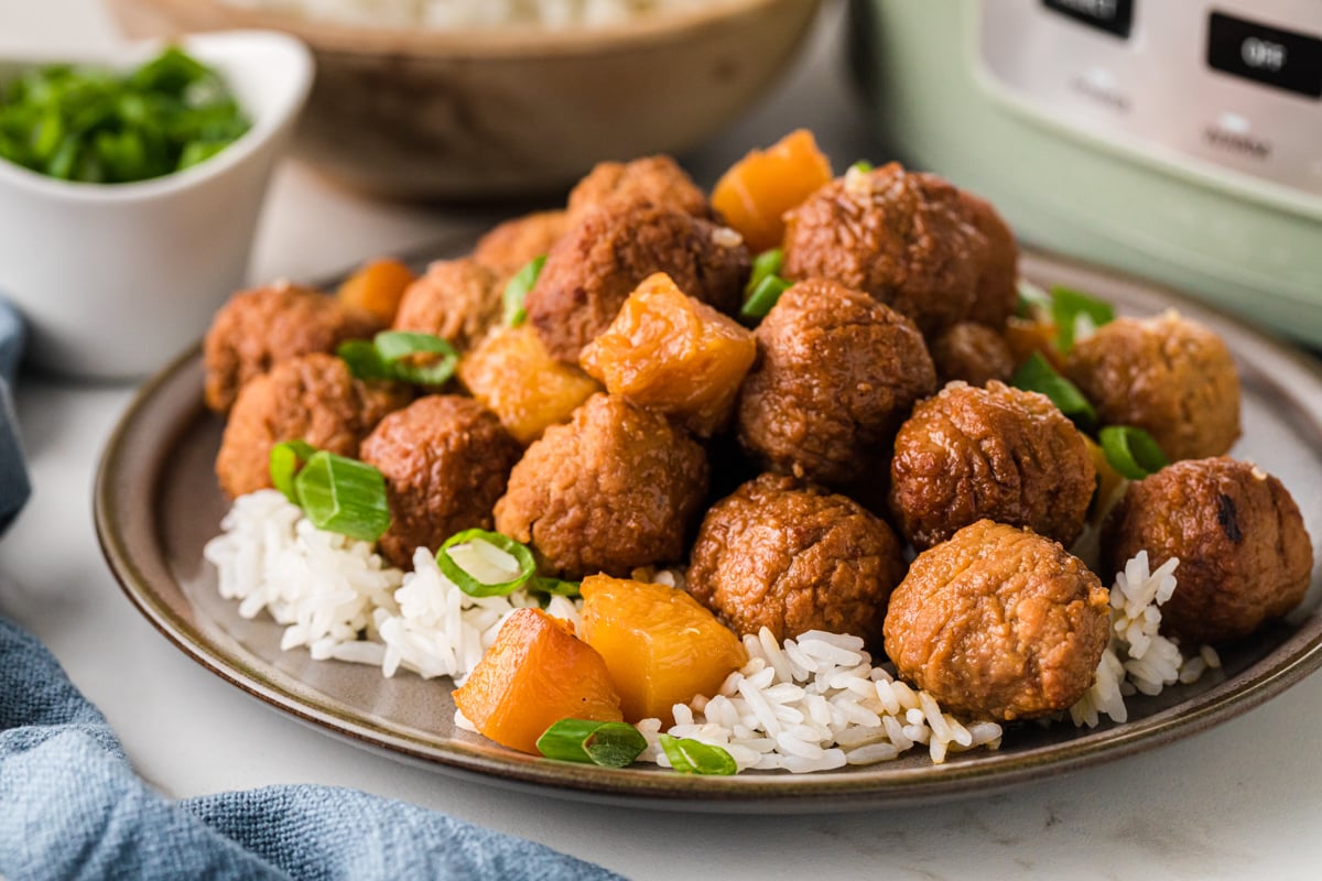 A serving of pineapple meatballs over white rice on a plate.
