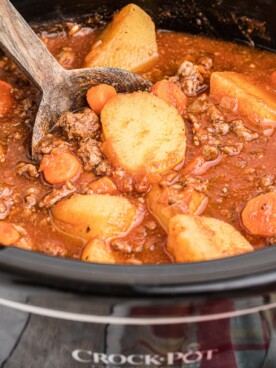 Side view of poor man's stew in crockpot with wooden spoon in it.