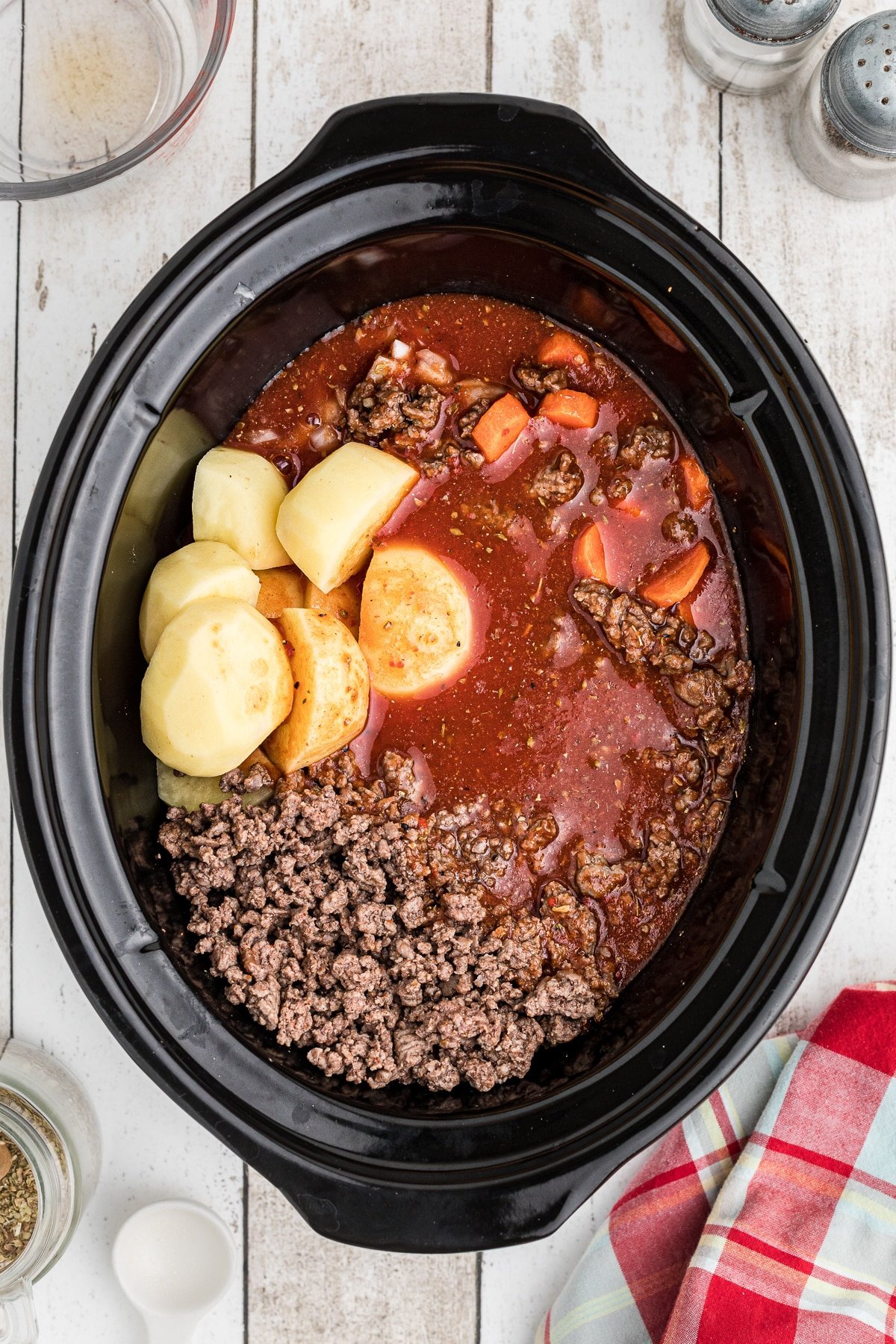 Tomato sauce poured into meat and veggies in crockpot.