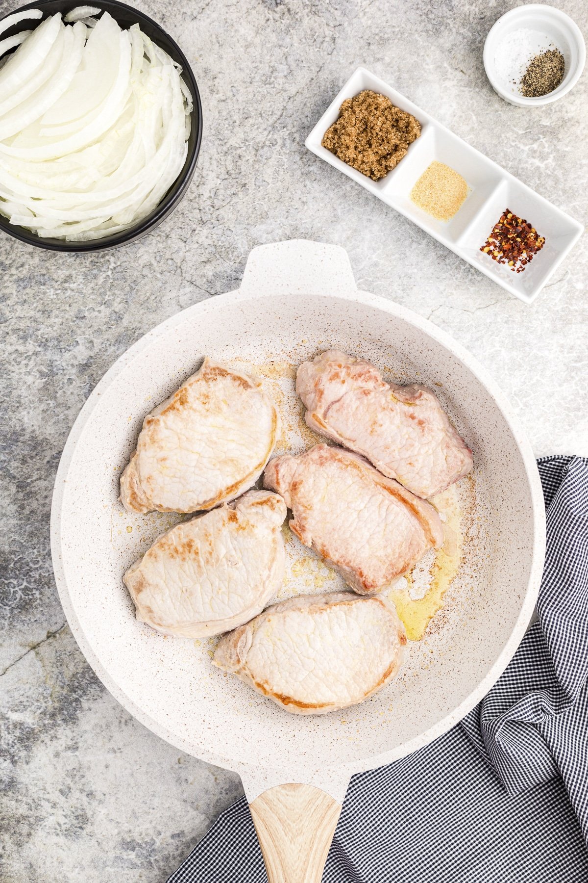 pork chops in a skillet being browned.