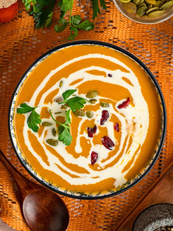 Slow cooker pumpkin soup in a bowl with a spoon next to it.