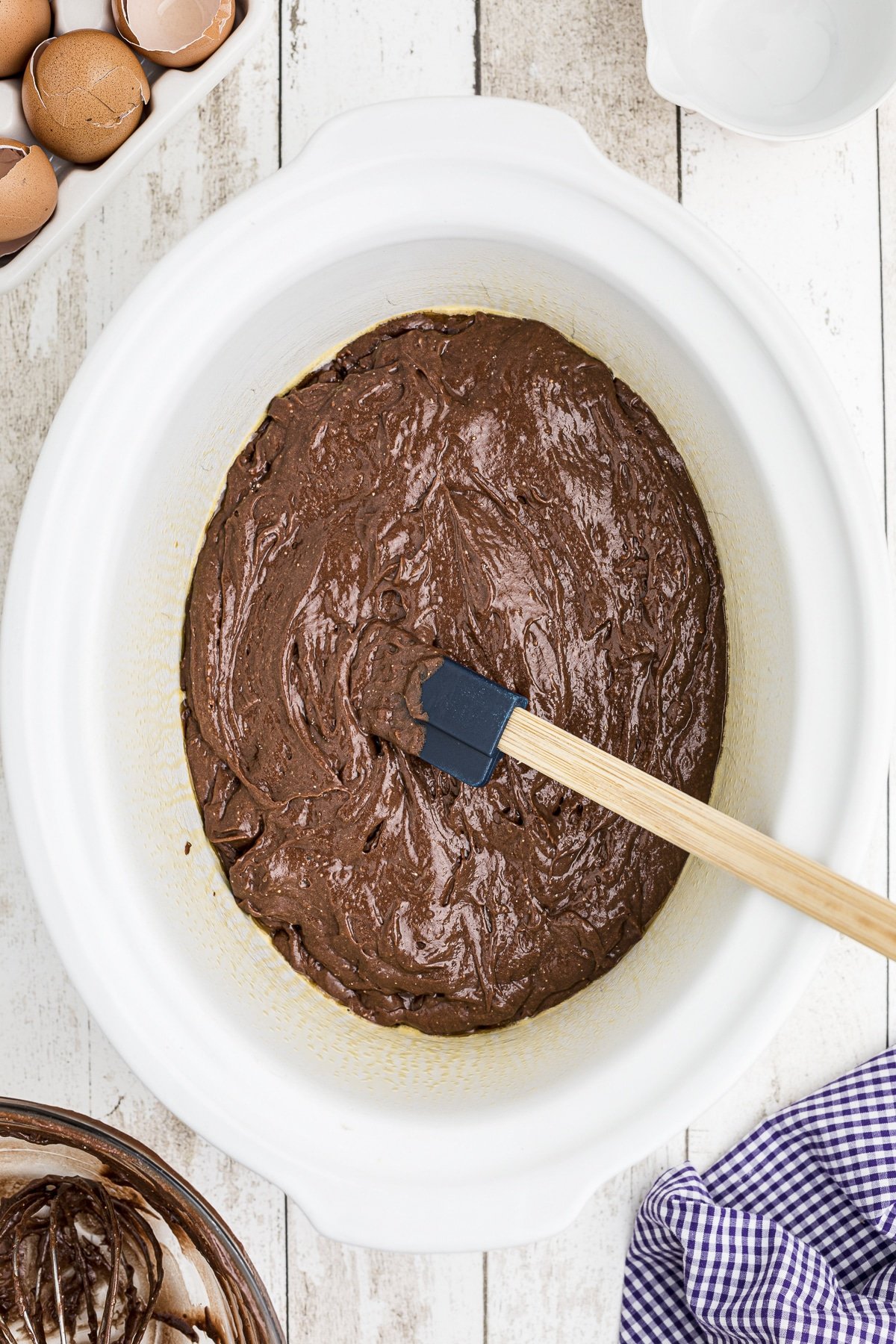 spread out chocolate cake batter in a slow cooker.