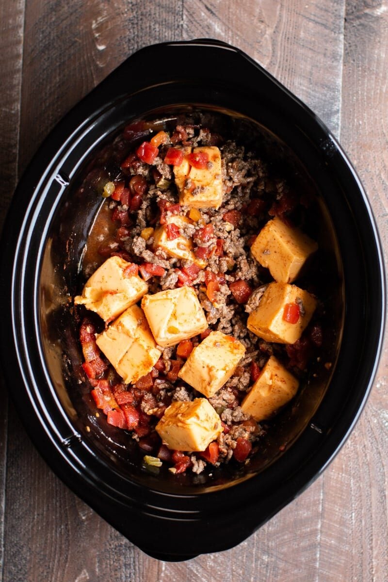 cubes of velveeta in slow cooker mixed with rotel and ground beef