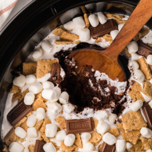 smores cake in a slow cooker with a wooden spoon in it.