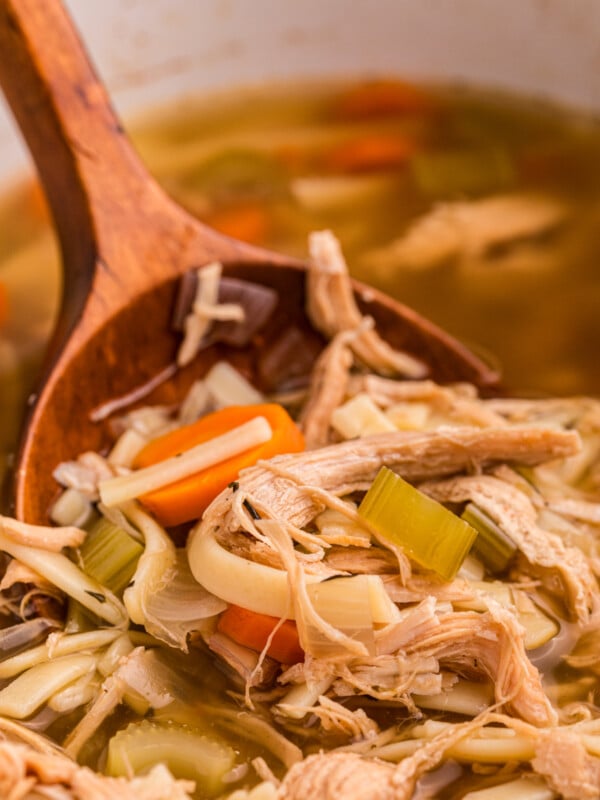 slow cooker turkey noodle soup with a wooden spoon.