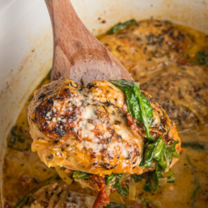 scooping a piece of tuscan chicken from a crockpot.